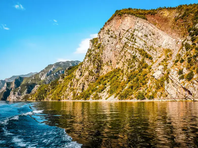Passenger ferry crossing the narrow Komani Lake gorge in morning light